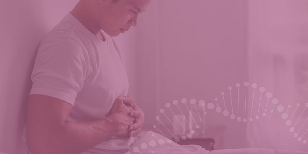 Um homem sentado na cama pressionando a região abdominal com as mãos. 